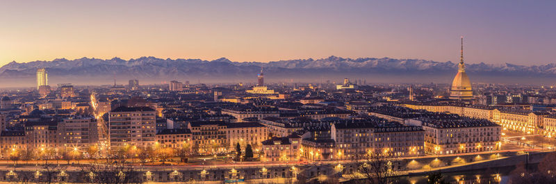 Illuminated cityscape against sky during sunset