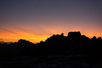 Scenic view of silhouette mountains against orange sky