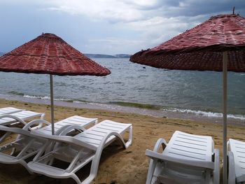 Chairs and table at beach against sky