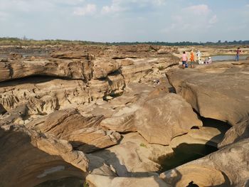 People on rock formations against sky