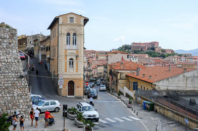 Vehicles on road amidst buildings in city against sky