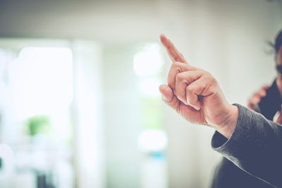 Cropped hand of business person pointing in office