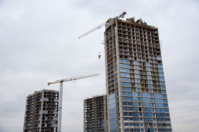 Tower cranes working at construction site against blue sky. crane lifting a concrete bucket. 