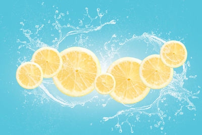 Lemon slices with water splash isolated on blue blackground.