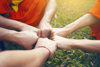 Cropped hands of friends giving fist bump over grassy field at park