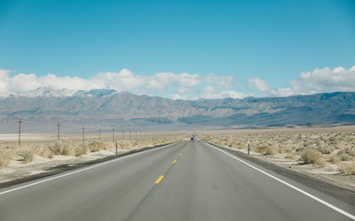 Empty road by mountains against sky