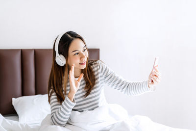 Young woman looking away while sitting on bed