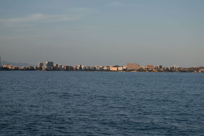 Sea by buildings against sky in city