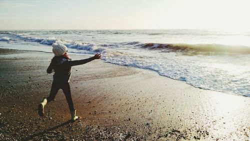 Girl running on beach against sky