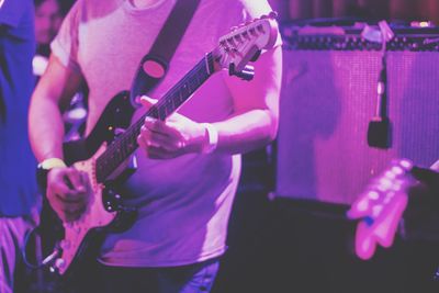 Midsection of man playing guitar