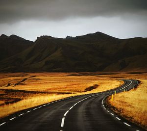 Empty road by mountains against sky