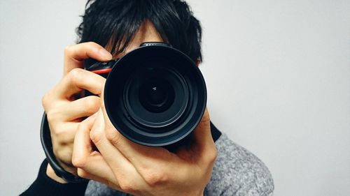 Close-up of man photographing against gray background