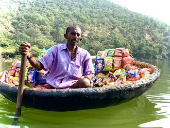 Man sitting in boat against river