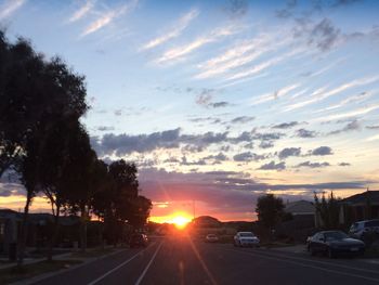 Cars on road against sky during sunset