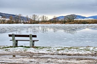 Scenic view of frozen lake by snowcapped mountains against sky