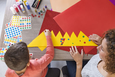 Mother and son making crafts at home with cardstocks and stickers