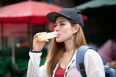 Beautiful backpacker drinking orange juice in city