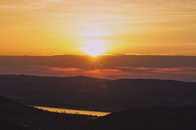 Scenic view of silhouette mountains against orange sky