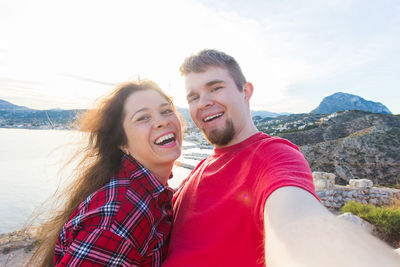 Portrait of smiling young couple against sky