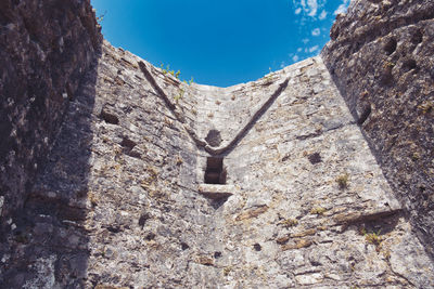 Low angle view of stone wall against sky