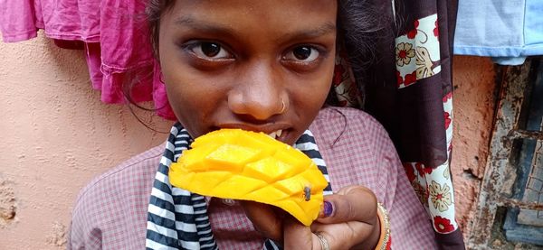 Close-up portrait of girl holding umbrella against wall