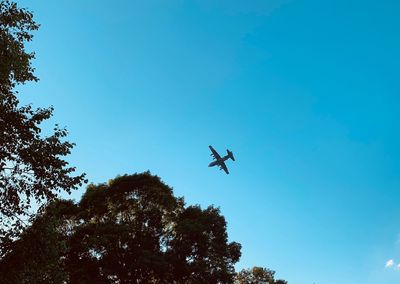 Low angle view of silhouette airplane against clear blue sky