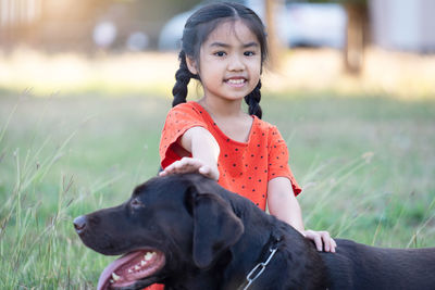 Portrait of girl with dog on field