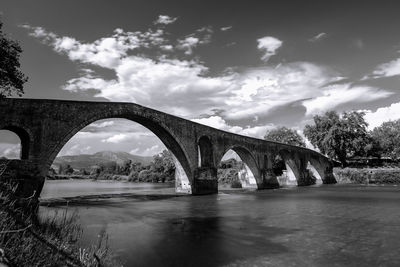 Arch bridge over river against sky