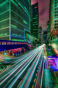 Light trails on city street amidst buildings at night