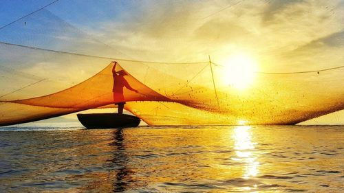 Boat sailing in sea against sky during sunset