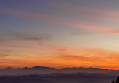 Scenic view of silhouette mountains against orange sky