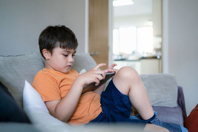 A boy using tablet learning online and doing homework on internet,cute kid playing game on touch pas