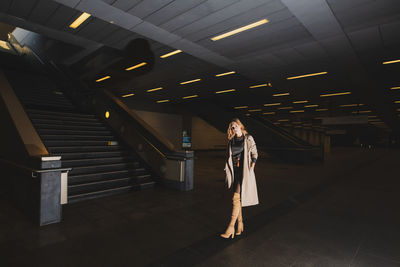 Woman standing in illuminated subway