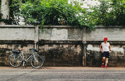 Man with bicycle standing against plants