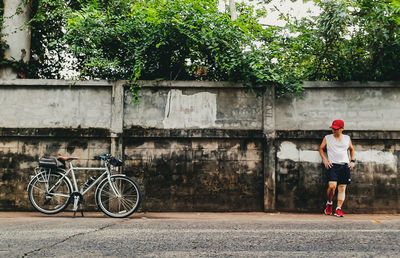 Man with bicycle standing against plants