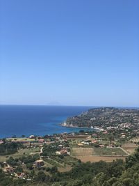 Aerial view of townscape by sea against clear blue sky