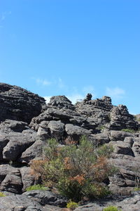 Low angle view of rocky mountains against blue sky