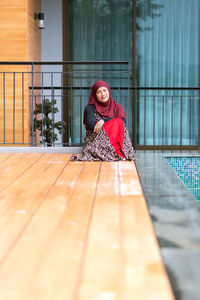Portrait of woman wearing hijab while sitting on poolside