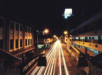 Light trails on street amidst buildings in city at night