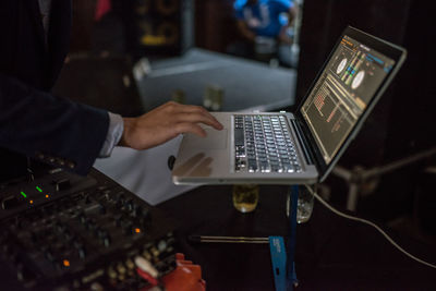 Midsection of man mixing music on laptop