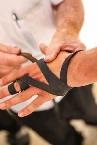 Midsection of man tying bandage on hand