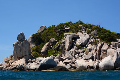 Rocks by sea against clear blue sky