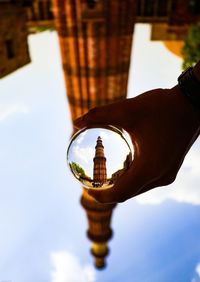 Low angle view of hand on building against sky