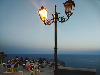 Street light by sea against clear sky during sunset