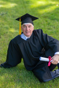 Portrait of woman wearing graduation gown standing on field