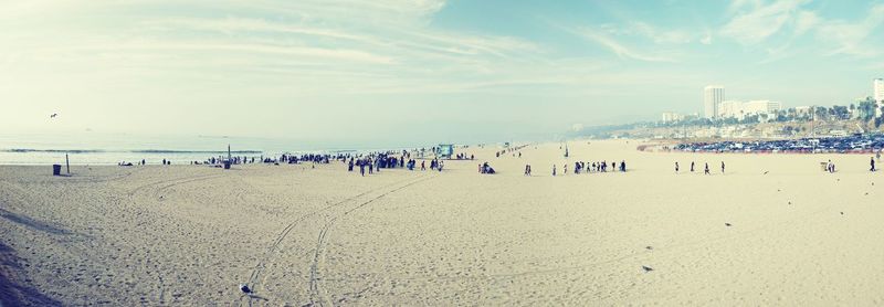 People at beach against sky during sunset