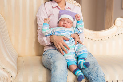 Low section of mother and daughter sitting on sofa at home