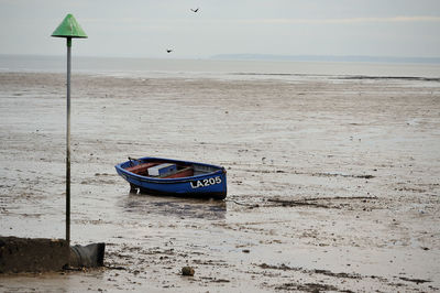 Boat moored on beach against sky