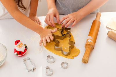 Children's hands, close-up, on a white table, cut out from the dough christmas figured cookies