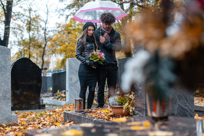 Couple standing with umbrella at cemetery